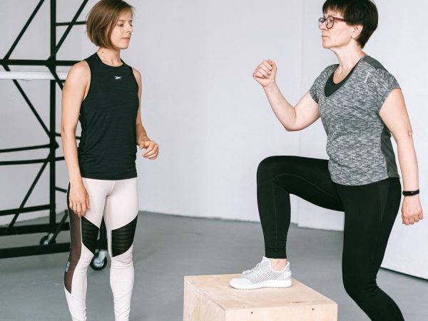 Fitness coach guides a woman in workout indoors. Focus on exercise and healthy lifestyle.